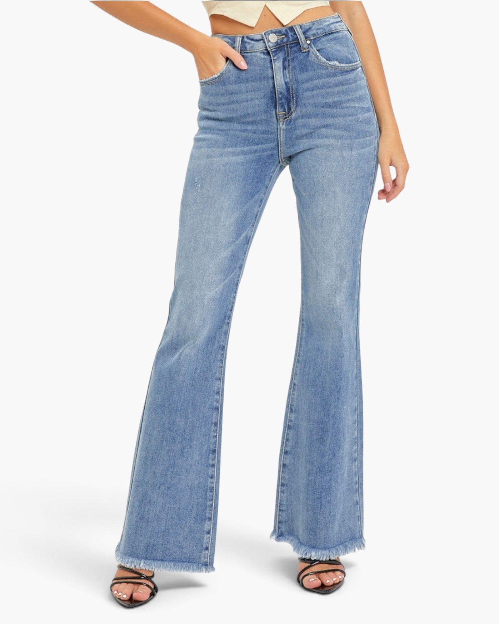 A model wearing light blue high-waisted flare jeans with a frayed hem and black heeled sandals, shown from the waist down against a plain white background.