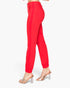 Red slim-fit pants shown from the side on a model, paired with clear high-heeled sandals against a plain white background.