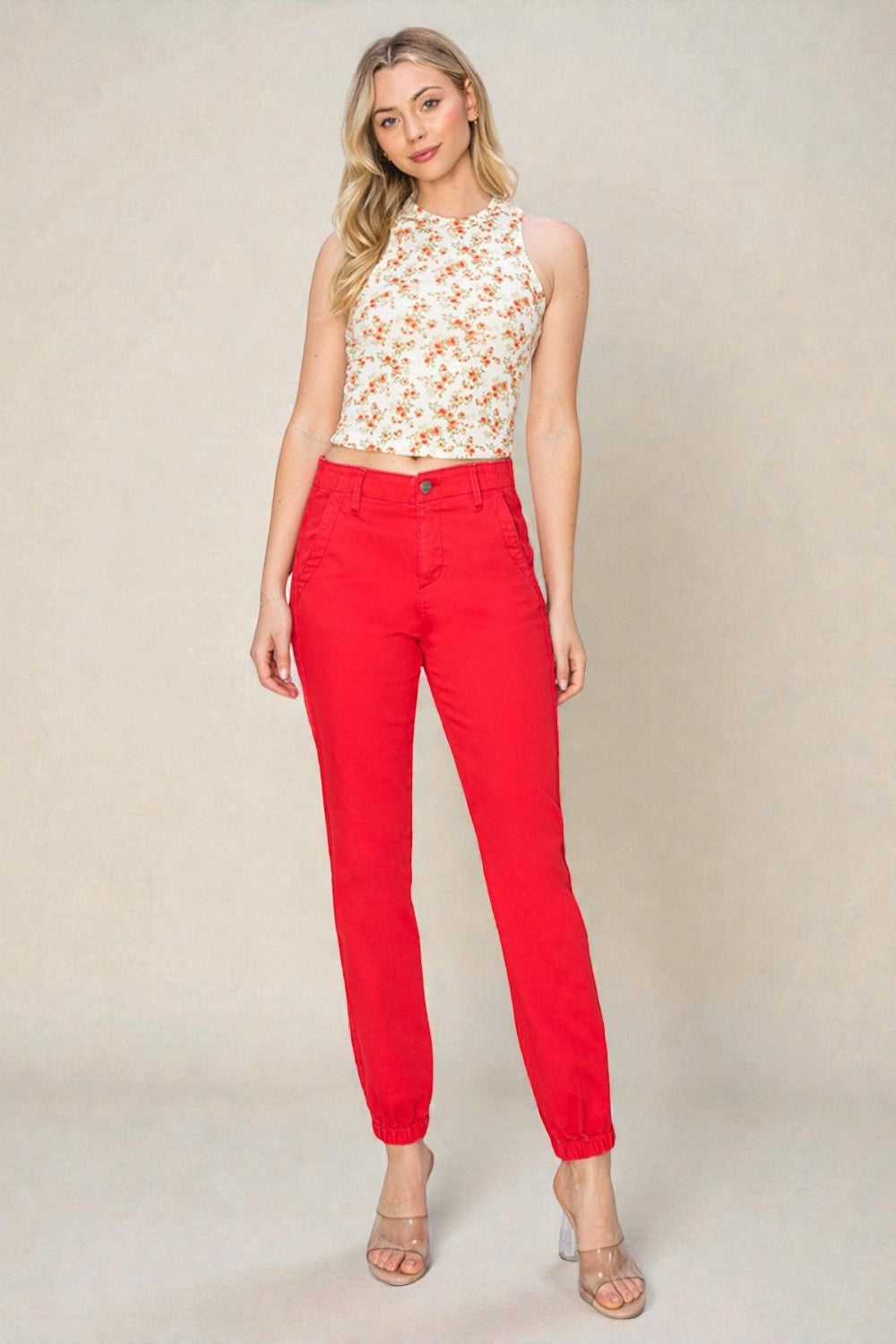 Woman wearing a floral top and red pants against a plain background