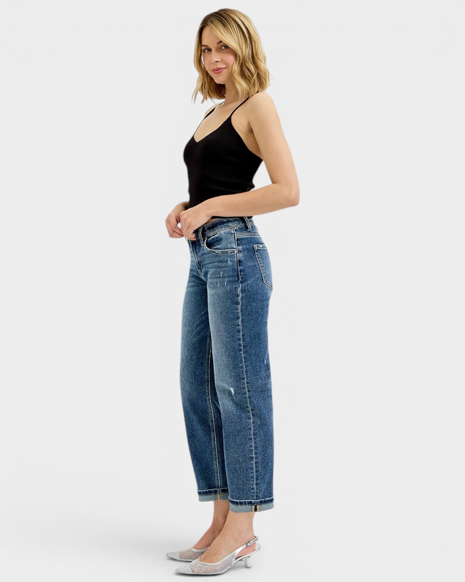 Woman wearing blue jeans and a black top on a white background