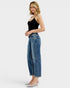 Woman wearing blue jeans and a black top on a white background