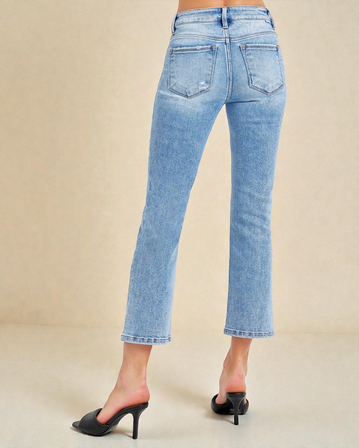Light blue jeans worn by a person on a beige background