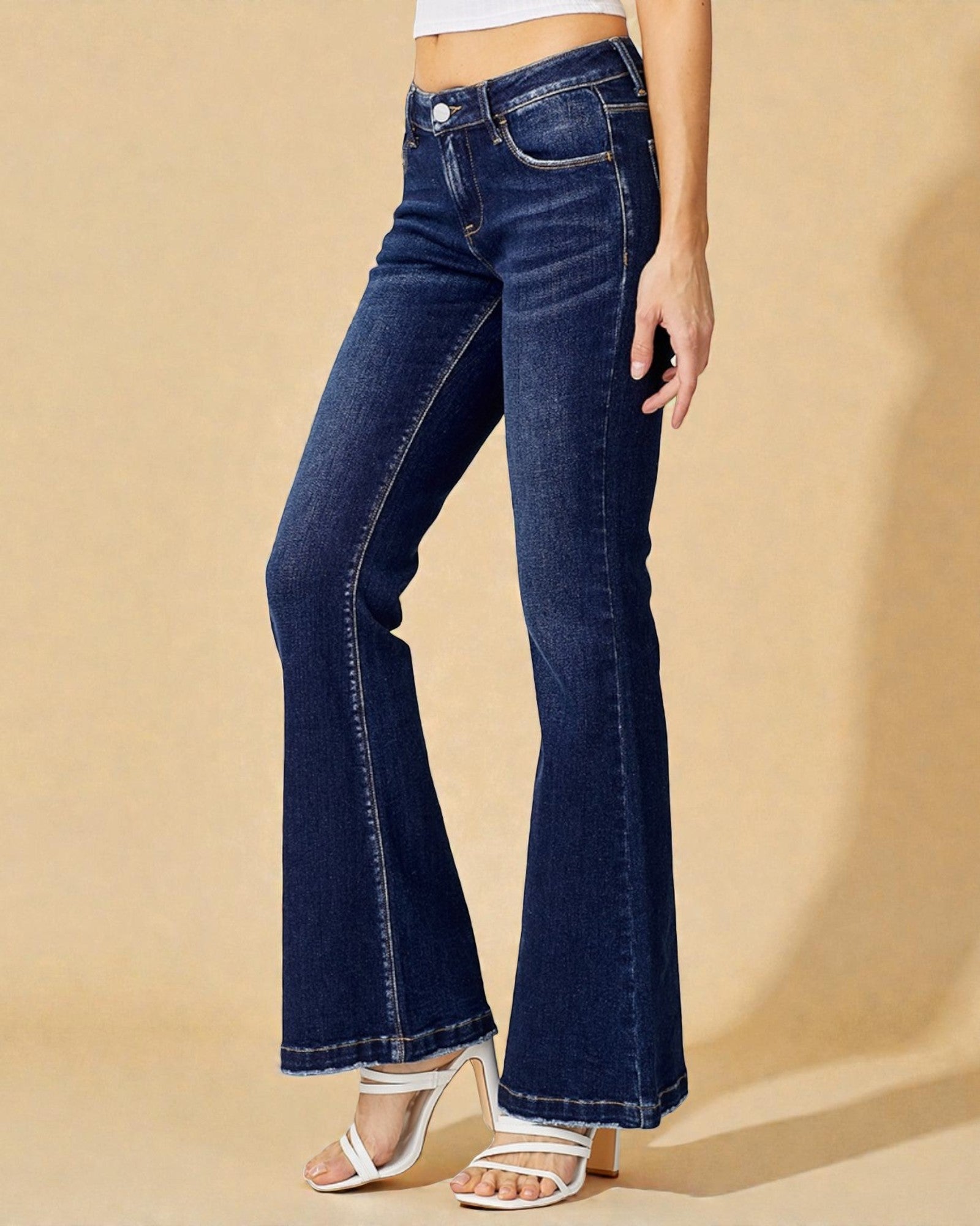 Blue flared jeans worn by a person on a beige background