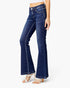 A model wearing dark blue flare jeans with white strappy high-heeled sandals, shown from the waist down on a light gray background.