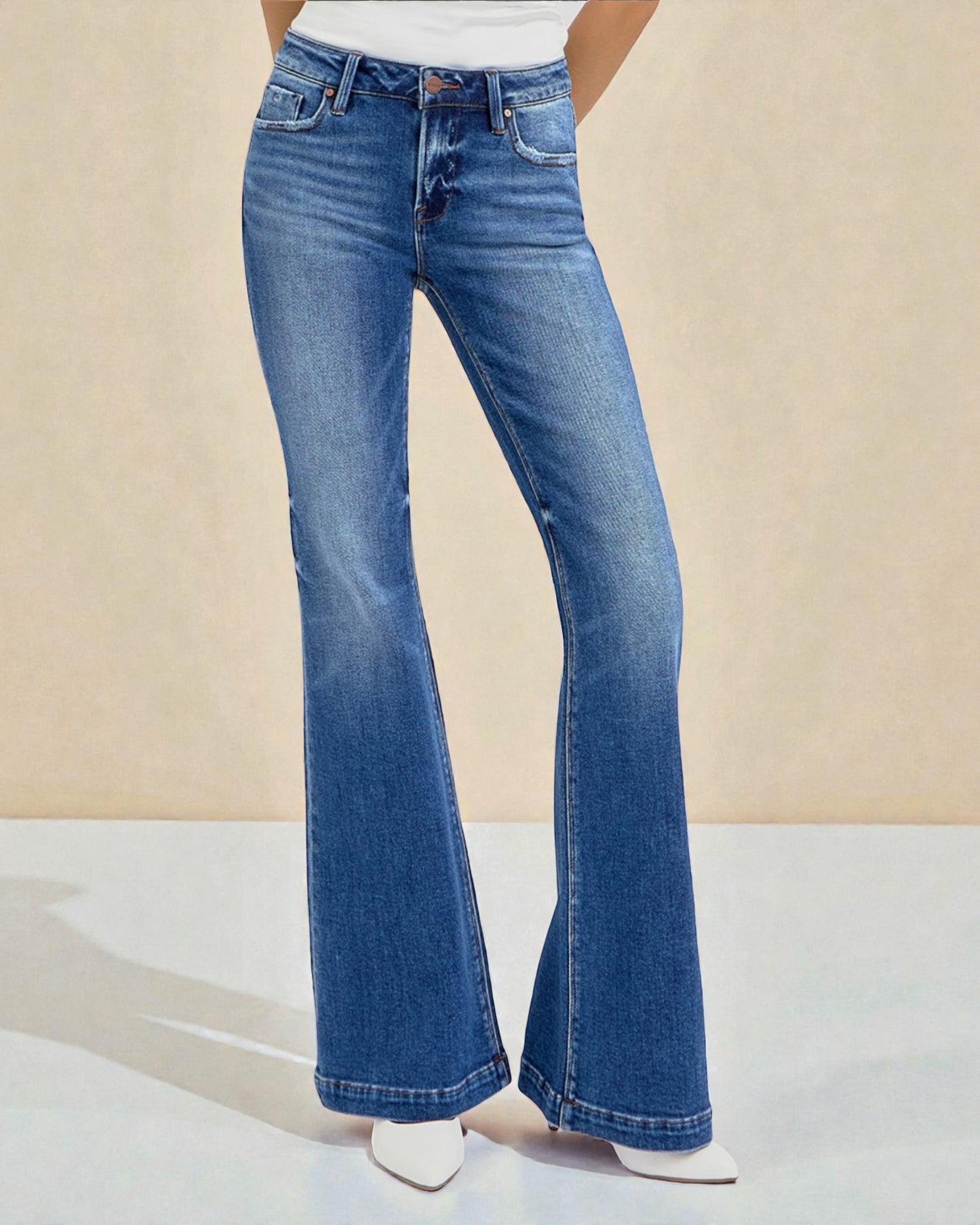 Blue flared jeans worn by a person on a beige background