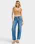 Woman wearing a beige crop top and blue jeans on a white background