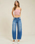 Woman wearing a pink strapless top and blue jeans against a plain background