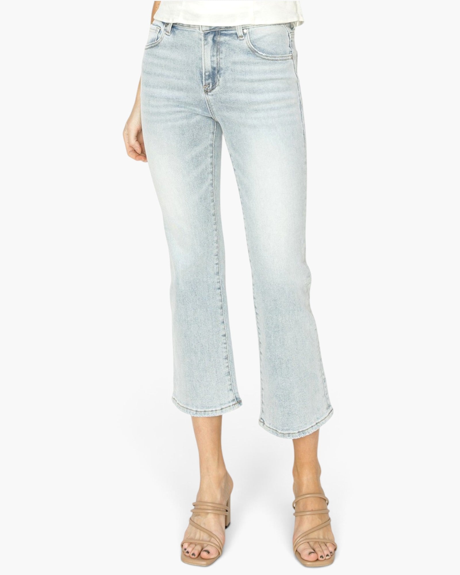A model wearing light-wash cropped flare jeans and beige strappy sandals against a plain white background.