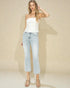 Woman wearing a white strapless top and light blue jeans against a beige background