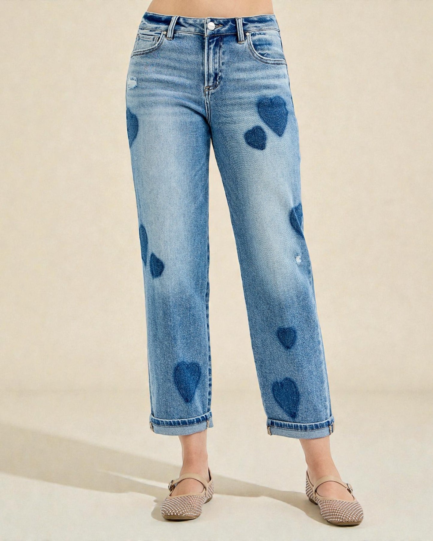 Blue jeans with heart-shaped distressing on a beige background