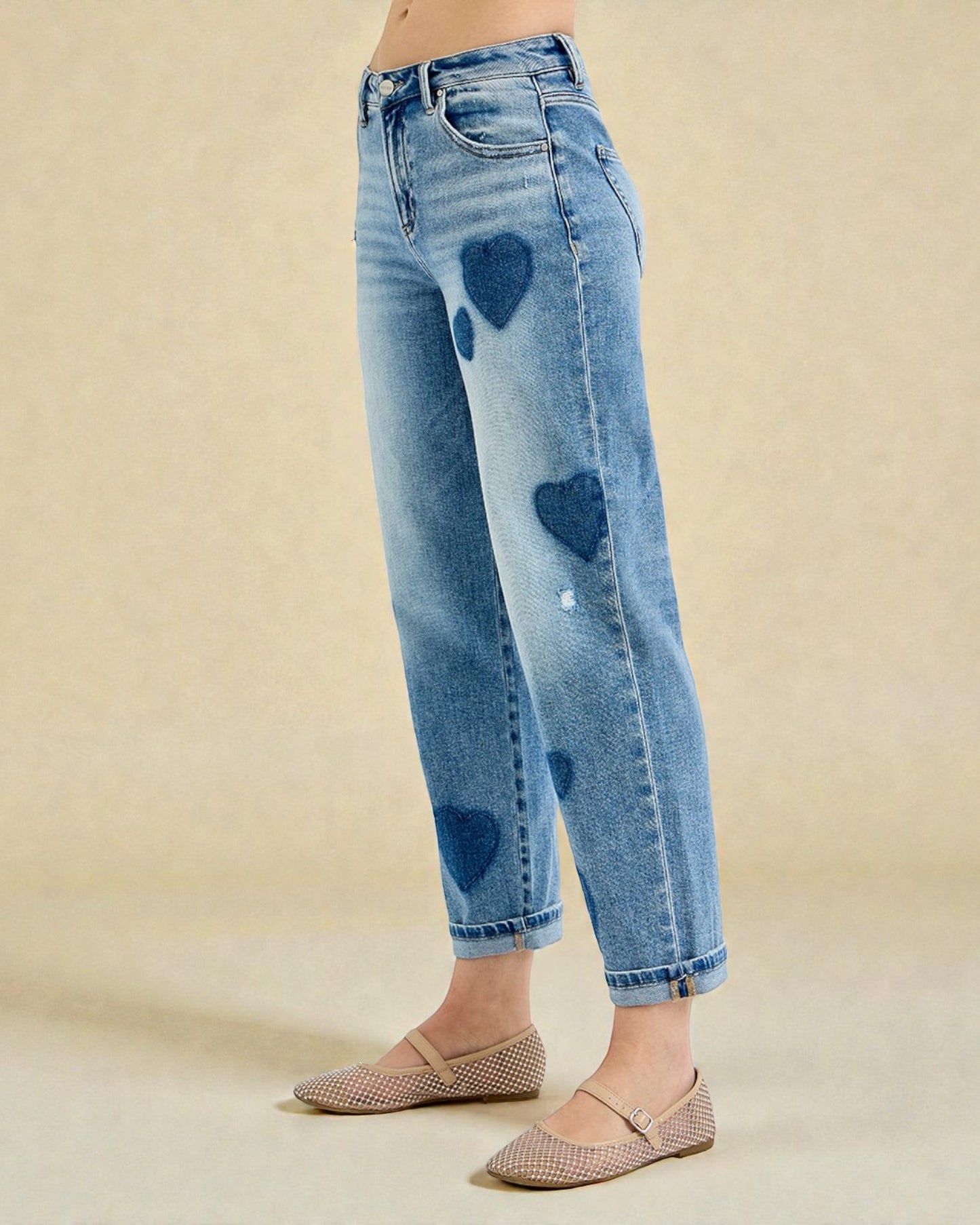 Blue jeans with heart-shaped patches on a beige background