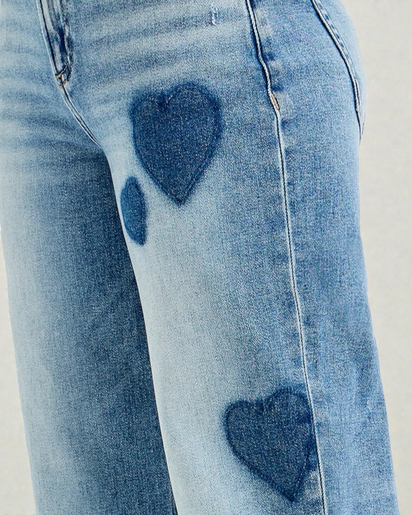 Blue jeans with heart-shaped distressing on a light gray background