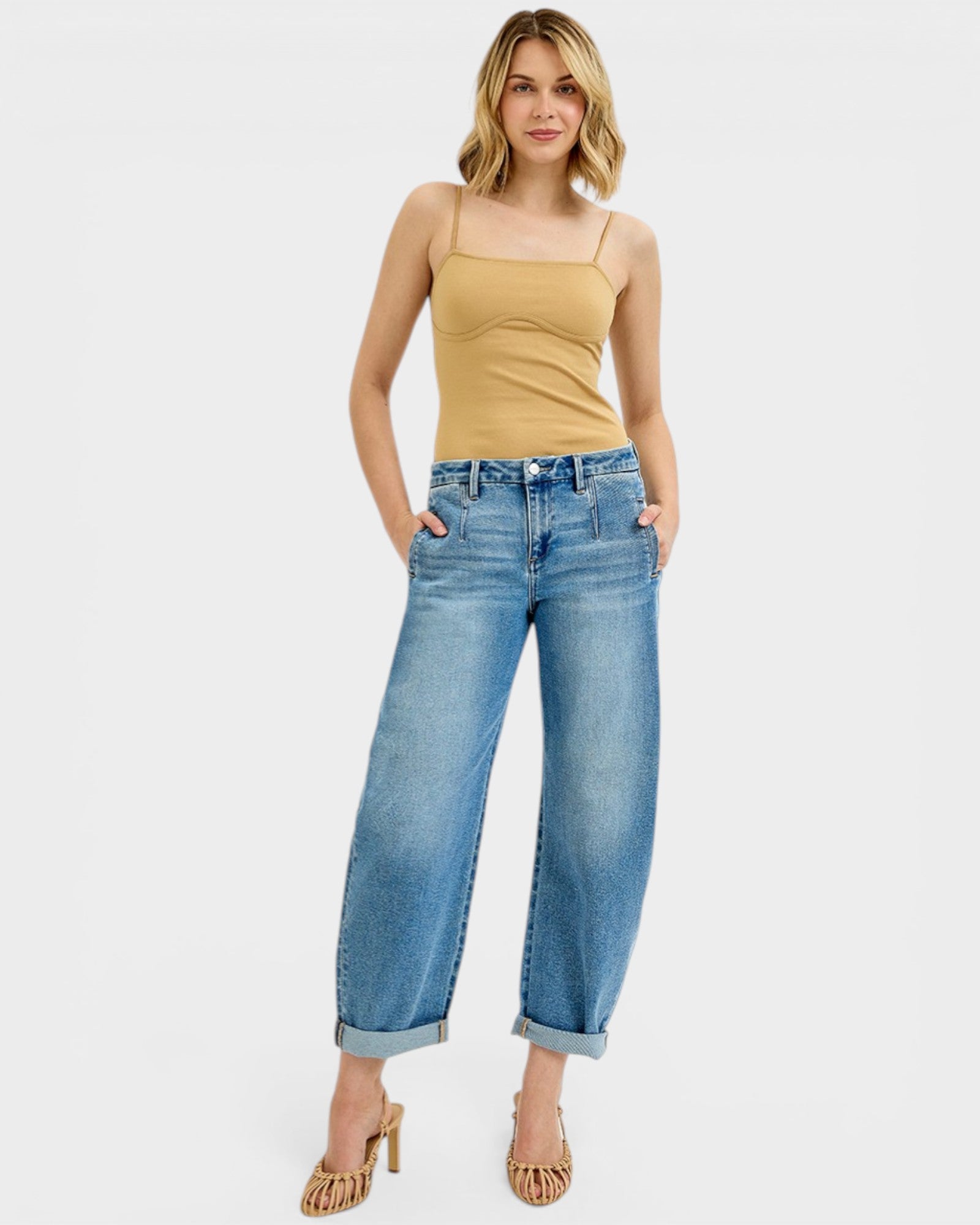 Woman wearing a mustard yellow top and blue jeans on a white background