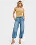 Woman wearing a mustard yellow top and blue jeans on a white background
