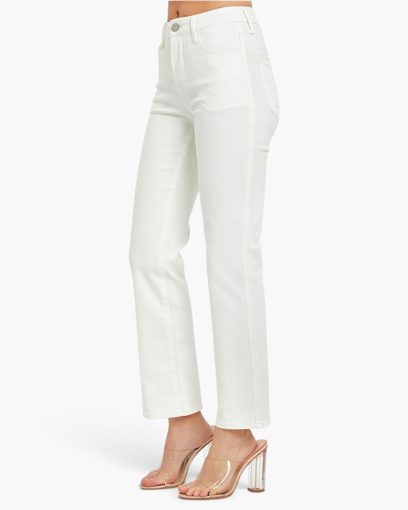 White cropped jeans shown on a model from the waist down, paired with clear strap high-heeled sandals against a clean white studio background.