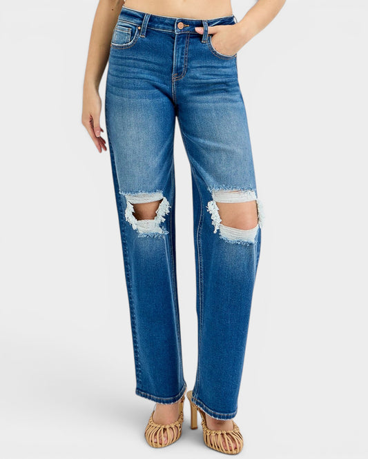 Blue jeans with distressed details worn by a person on a white background