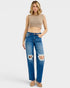 Woman wearing a beige crop top and blue jeans with a white background