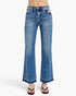 A person wearing medium-wash blue denim flare jeans with a straight rise and wide legs, paired with black flip-flop sandals, shown against a plain light gray studio background.