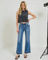 Woman wearing a black sleeveless top and blue jeans on a white background