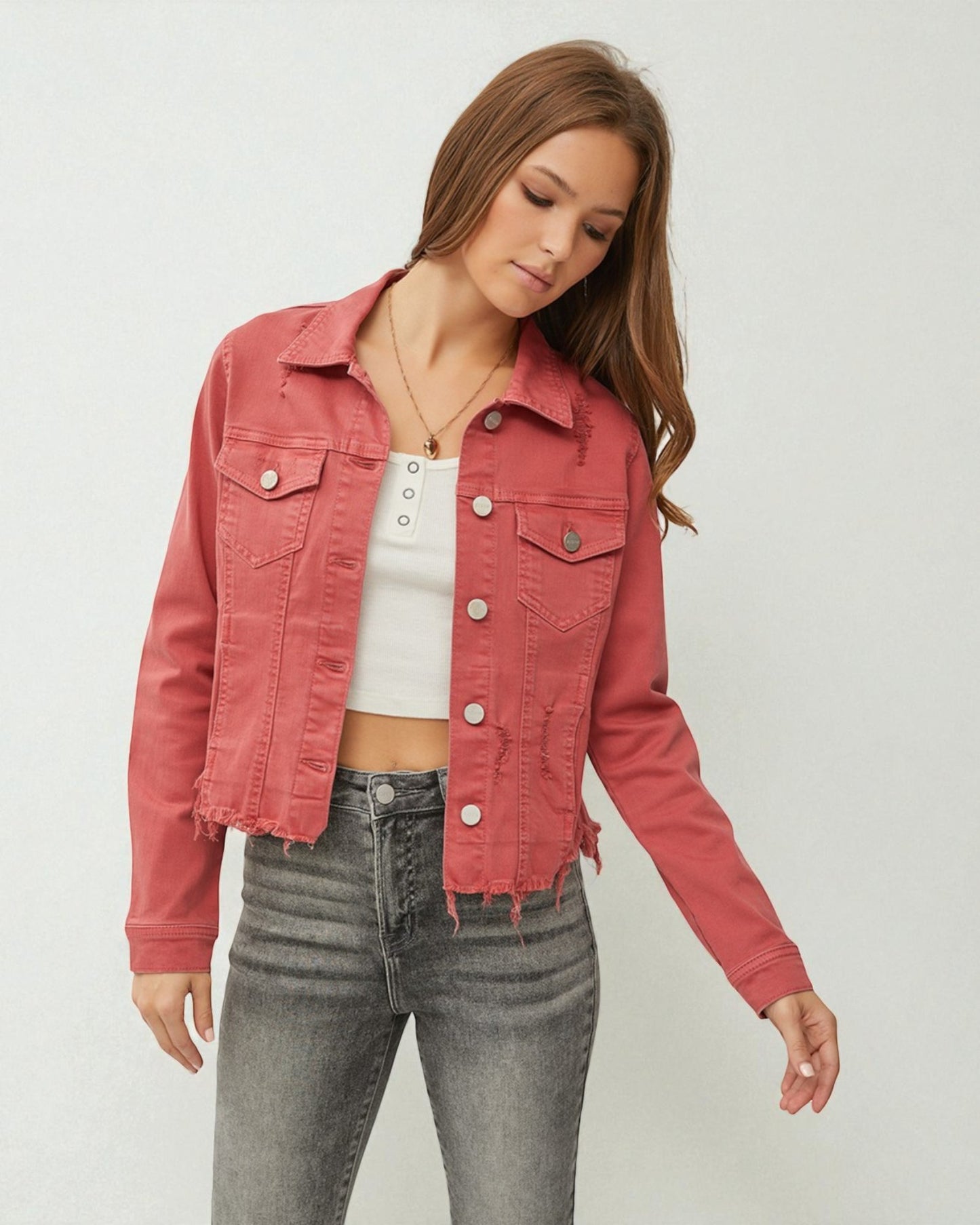 Woman wearing a pink denim jacket and gray jeans on a white background