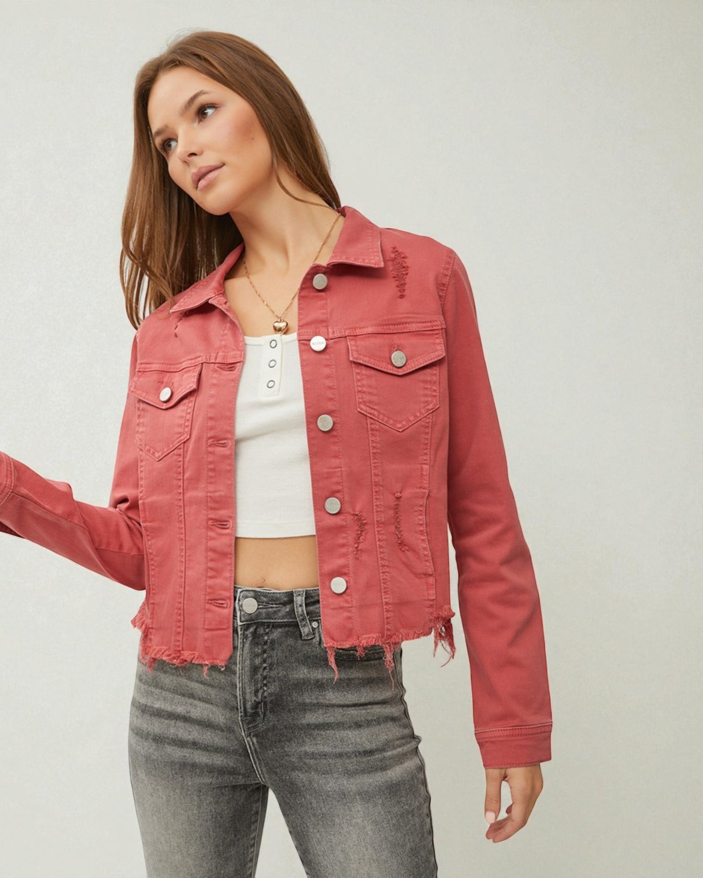 Woman wearing a pink denim jacket on a plain background