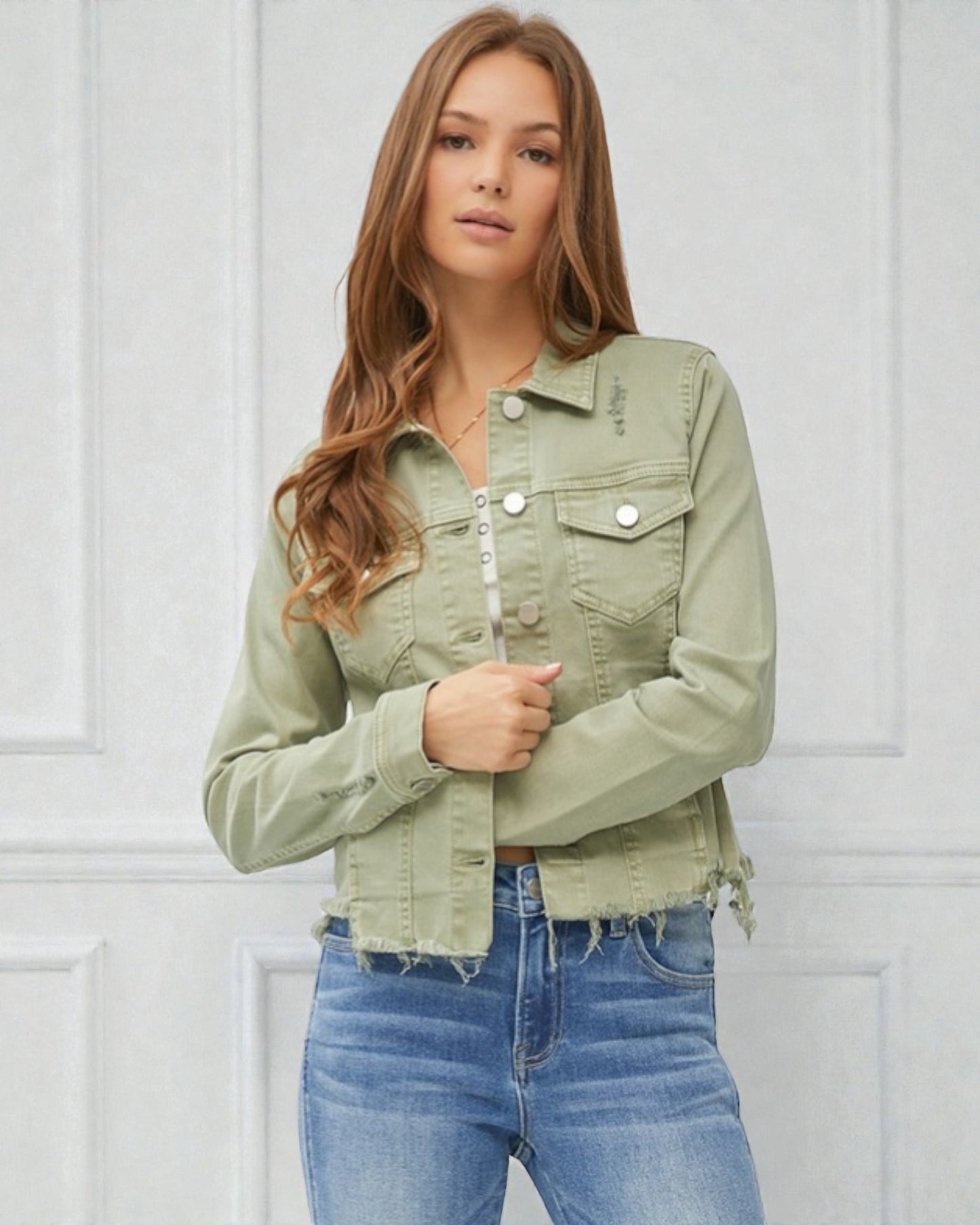 Woman wearing a green denim jacket and blue jeans against a white background