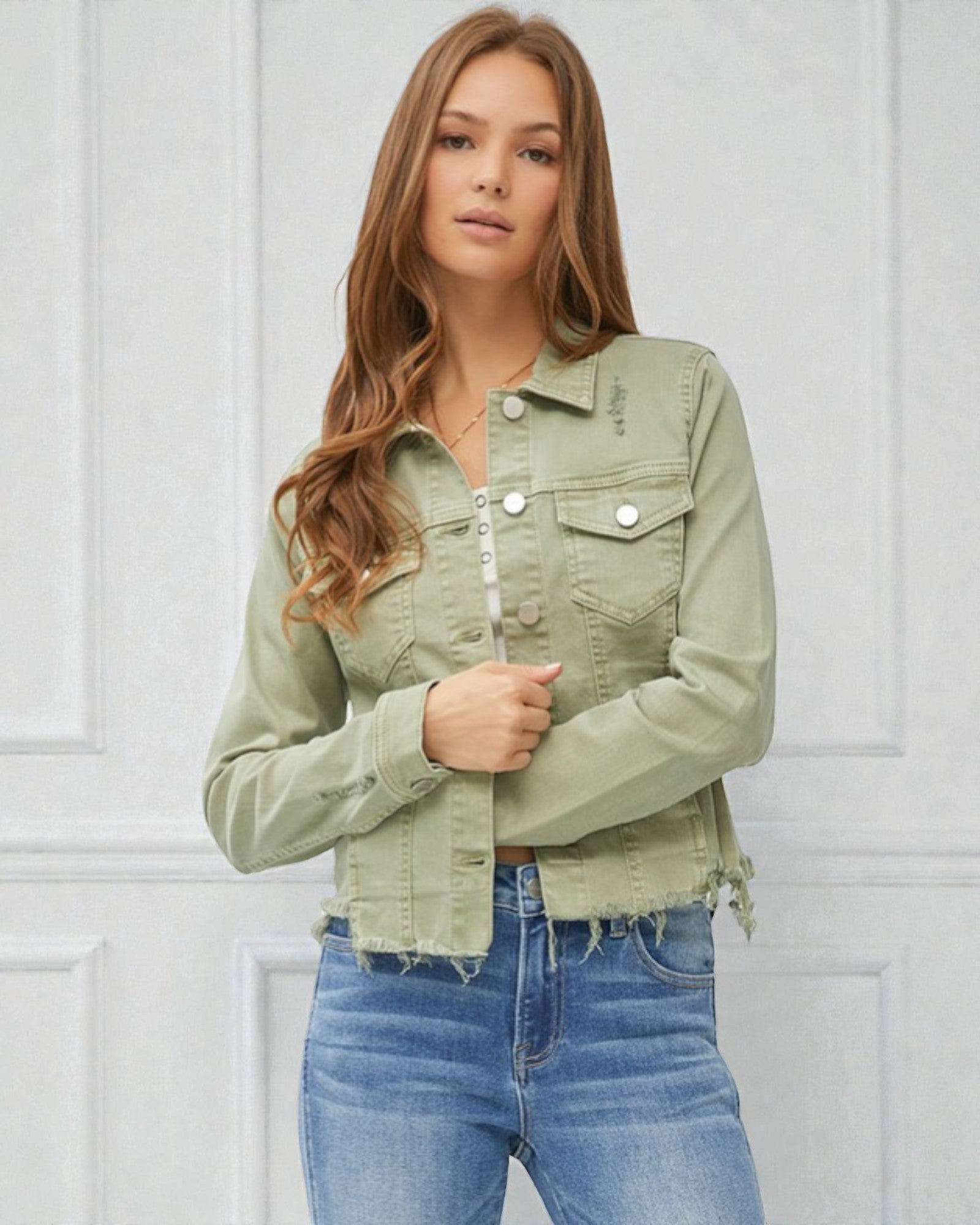 Woman wearing a green denim jacket and blue jeans against a white background