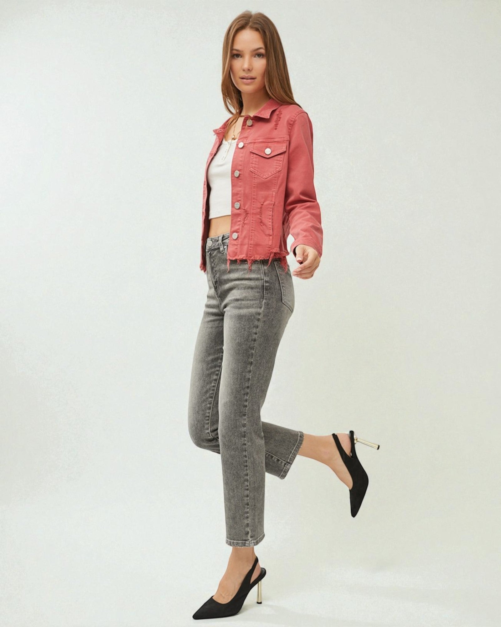 Woman wearing a red denim jacket, white top, and gray jeans on a white background