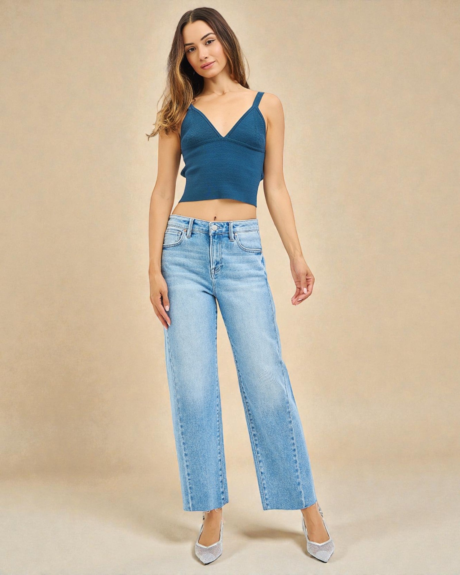 Woman wearing a blue top and light blue jeans on a beige background