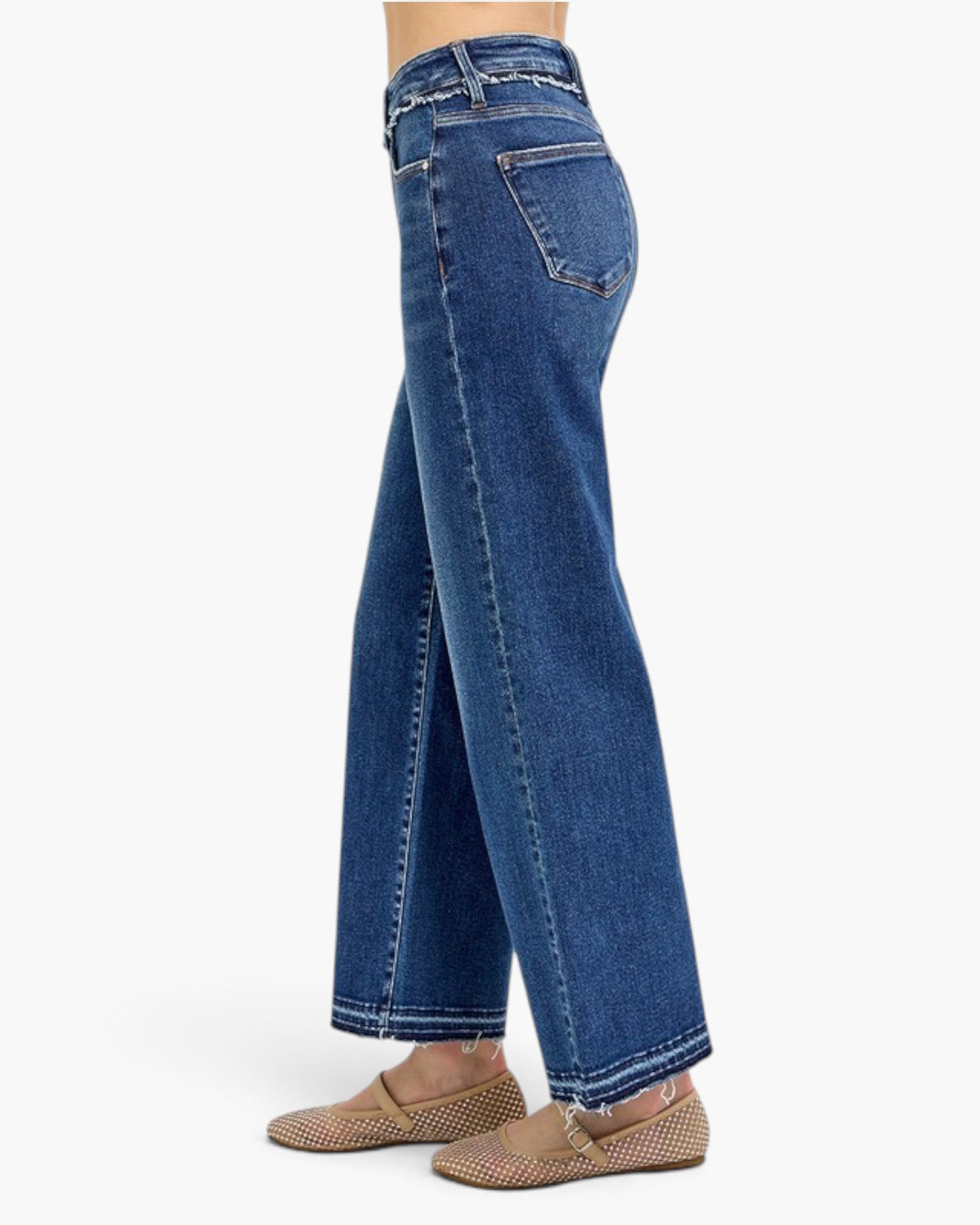 A side profile view of a person wearing blue wide-leg cropped jeans and tan woven flat shoes against a plain white background.
