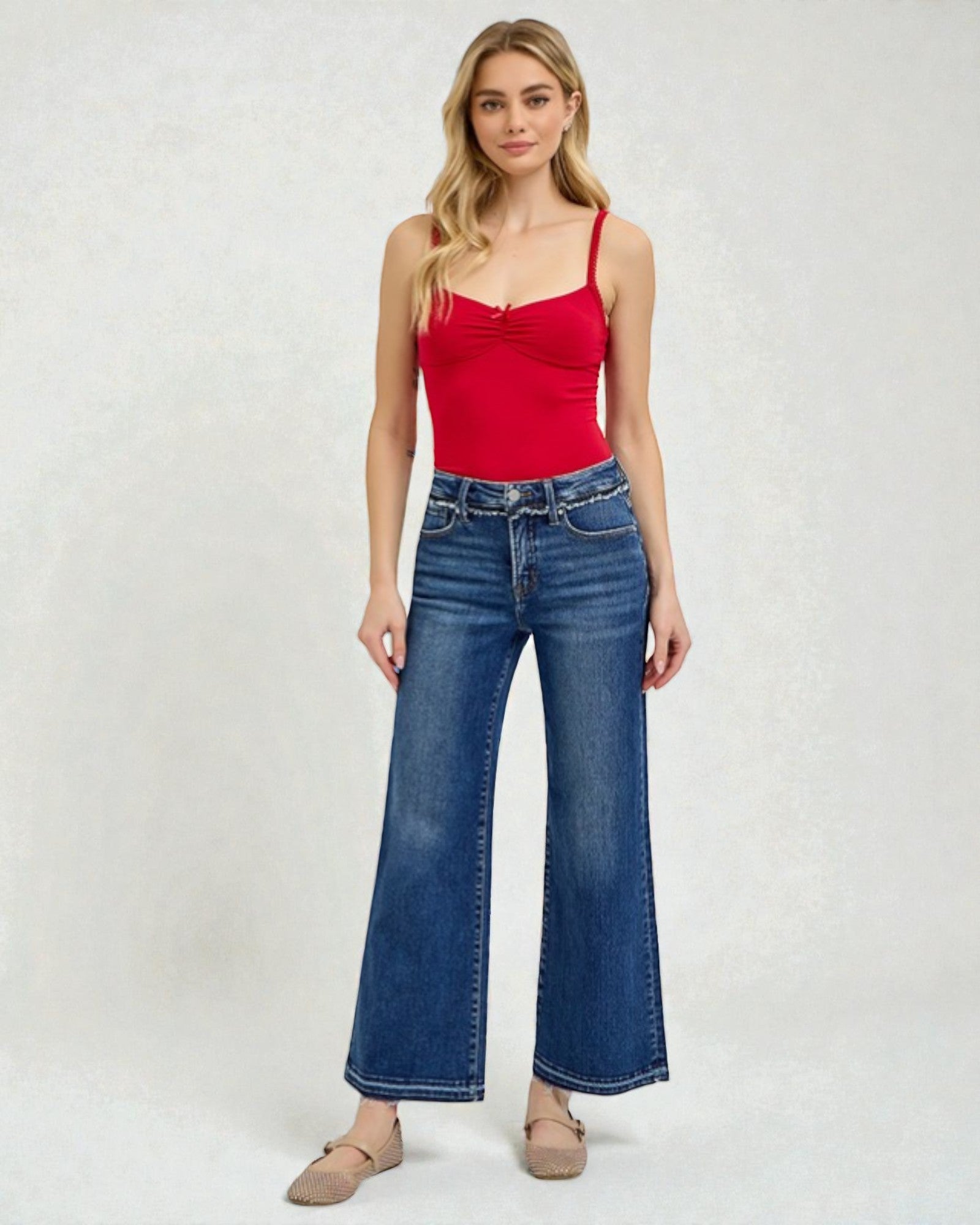 Woman wearing a red top and blue jeans on a white background