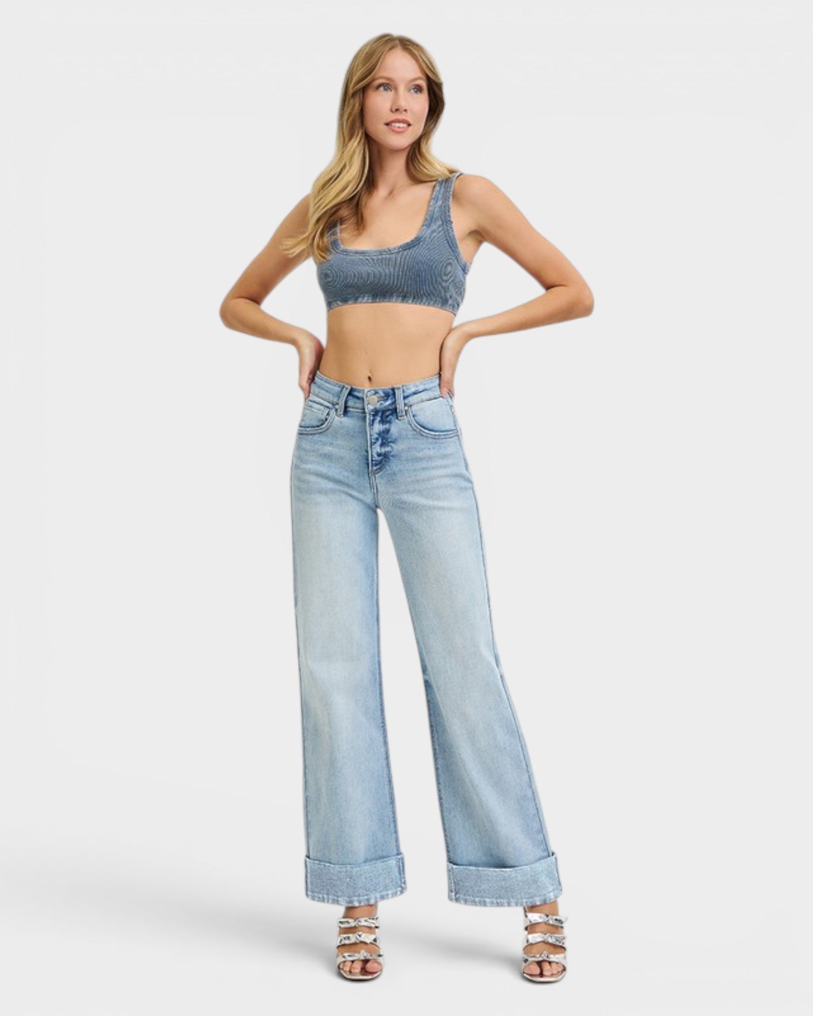 Woman wearing a denim crop top and wide-leg jeans on a white background