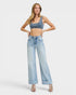 Woman wearing a denim crop top and wide-leg jeans on a white background