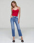 Woman wearing a red top and blue jeans on a plain background