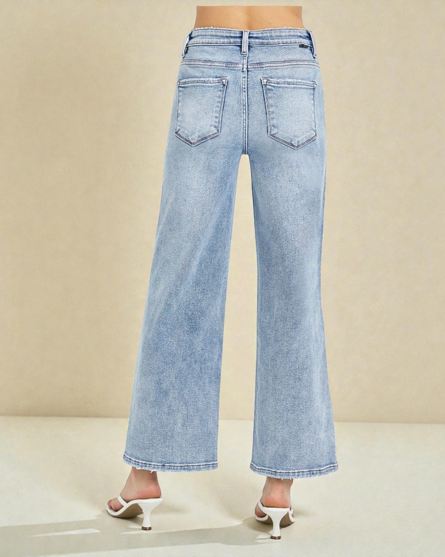 Light blue jeans worn by a person on a beige background