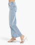 Light wash blue cropped flare jeans shown on a model from the side, paired with white heeled thong sandals against a clean white studio background.