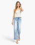 A woman modeling a pair of light-wash wide-leg cropped jeans with a white sleeveless knit top, standing against a plain white studio background.