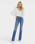 Woman wearing a white sweater and blue jeans on a white background