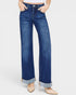 Person wearing blue jeans with rolled-up cuffs on a white background