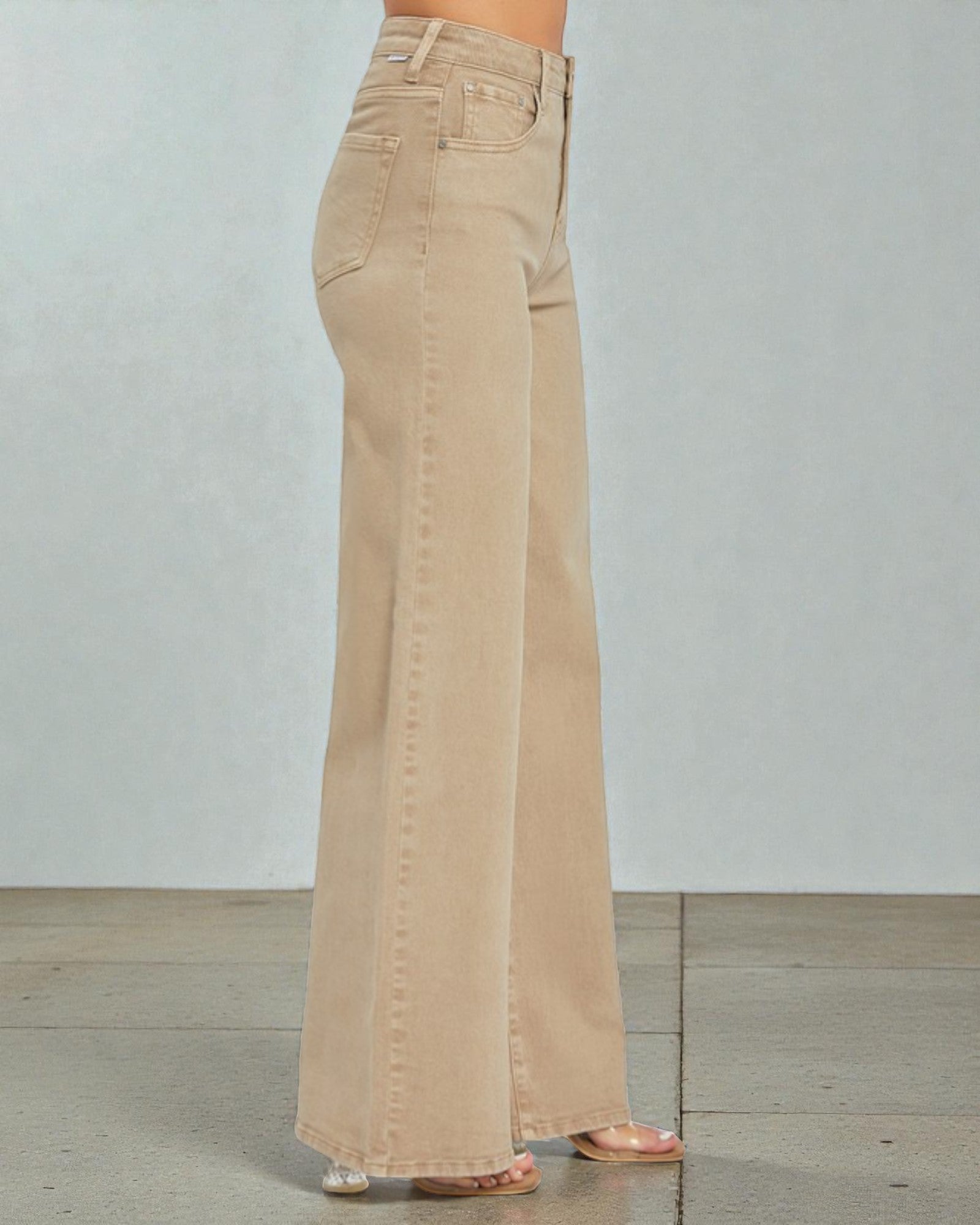 Beige wide-leg jeans worn by a person on a light gray background