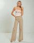 Woman wearing a strapless Coca-Cola top and beige pants on a white background