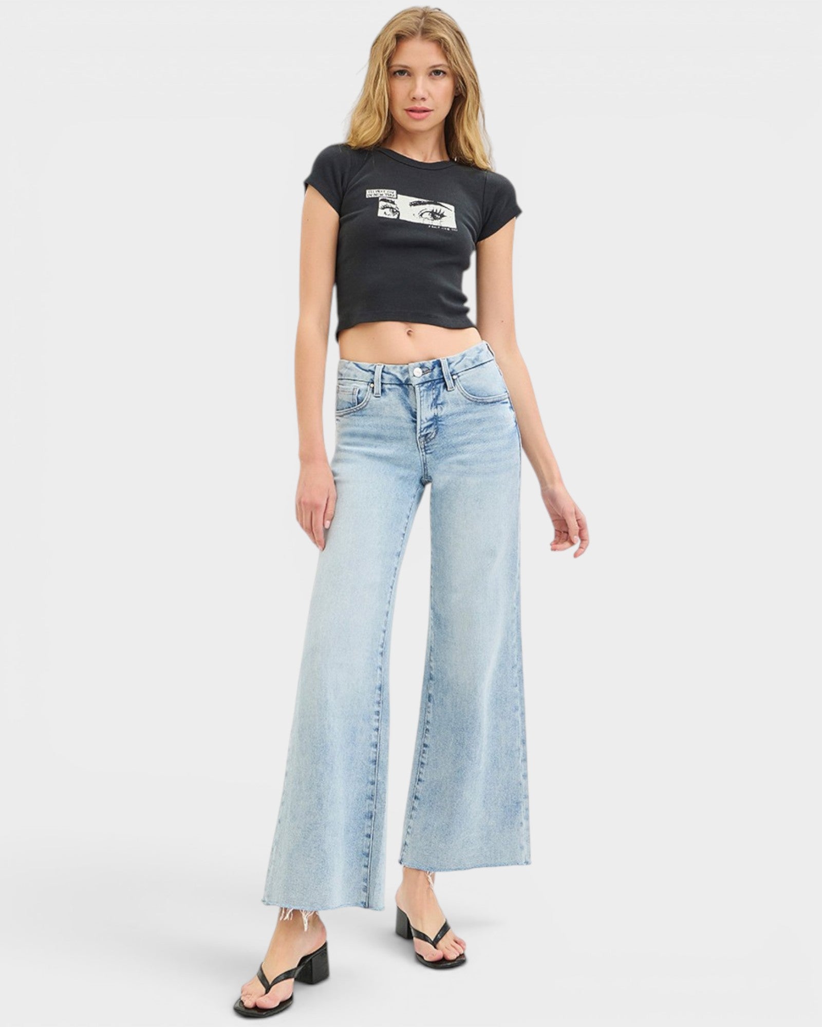 Woman wearing a black t-shirt and light blue jeans on a white background