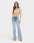 Woman wearing a beige crop top and light blue jeans on a white background