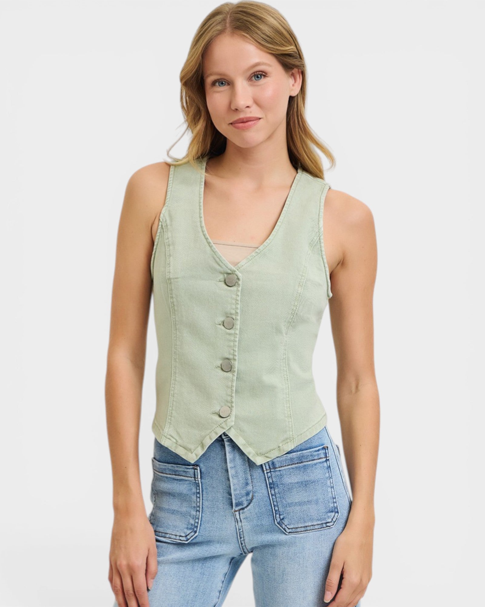 Woman wearing a light green denim vest over a white background