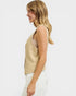 Woman wearing a beige sleeveless top and white pants on a white background