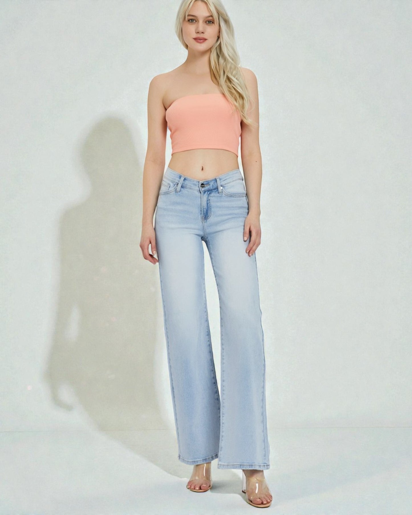 Woman wearing a strapless top and light blue jeans on a white background