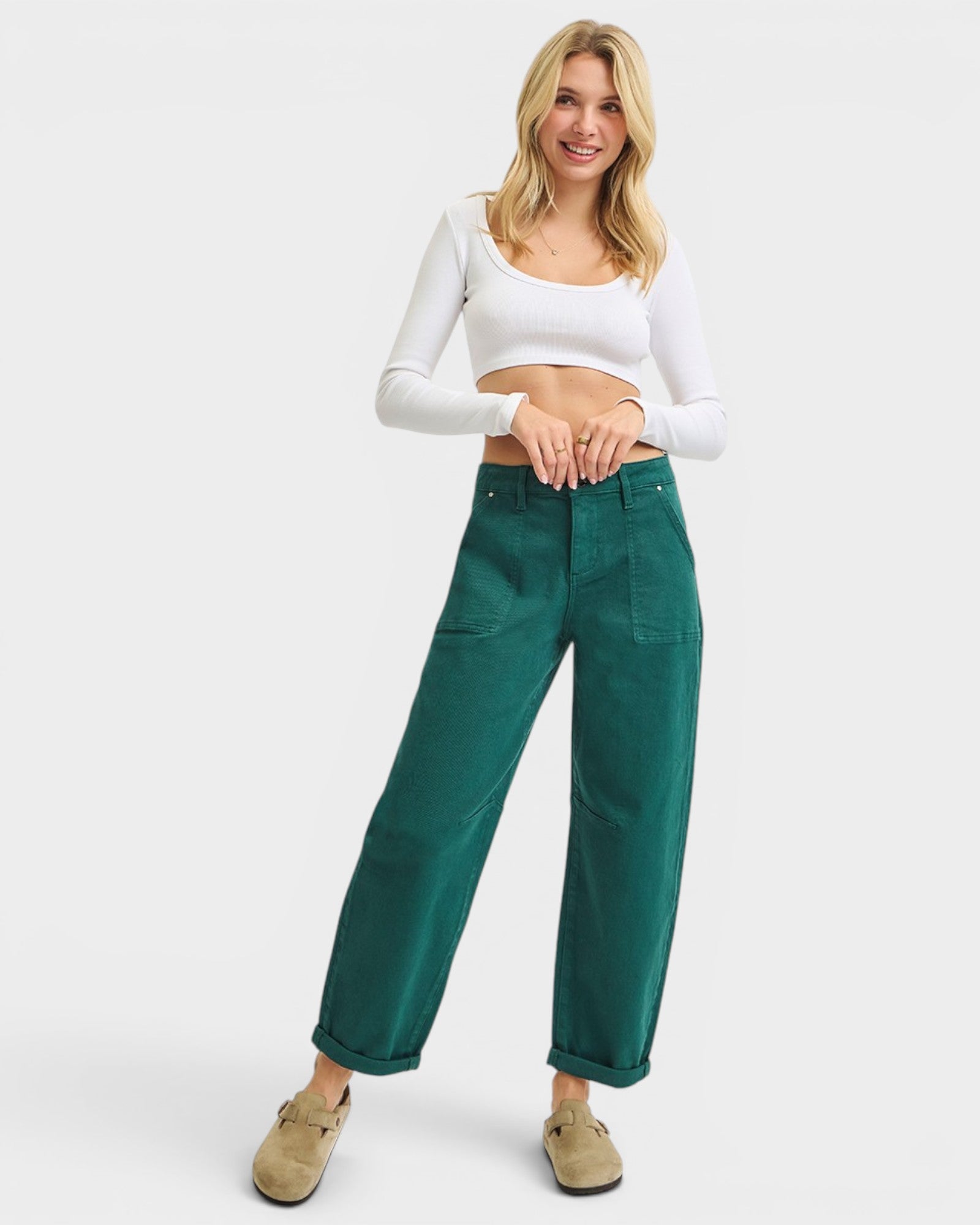 Woman wearing green pants and a white top on a white background
