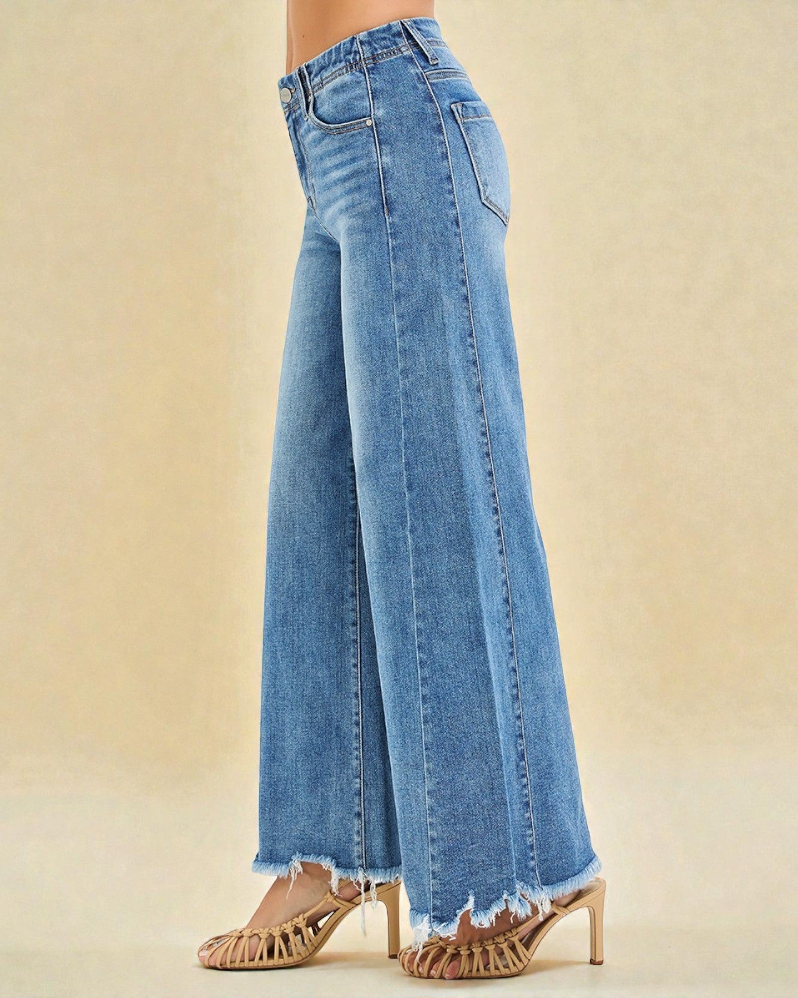 Blue wide-leg jeans worn by a person on a beige background