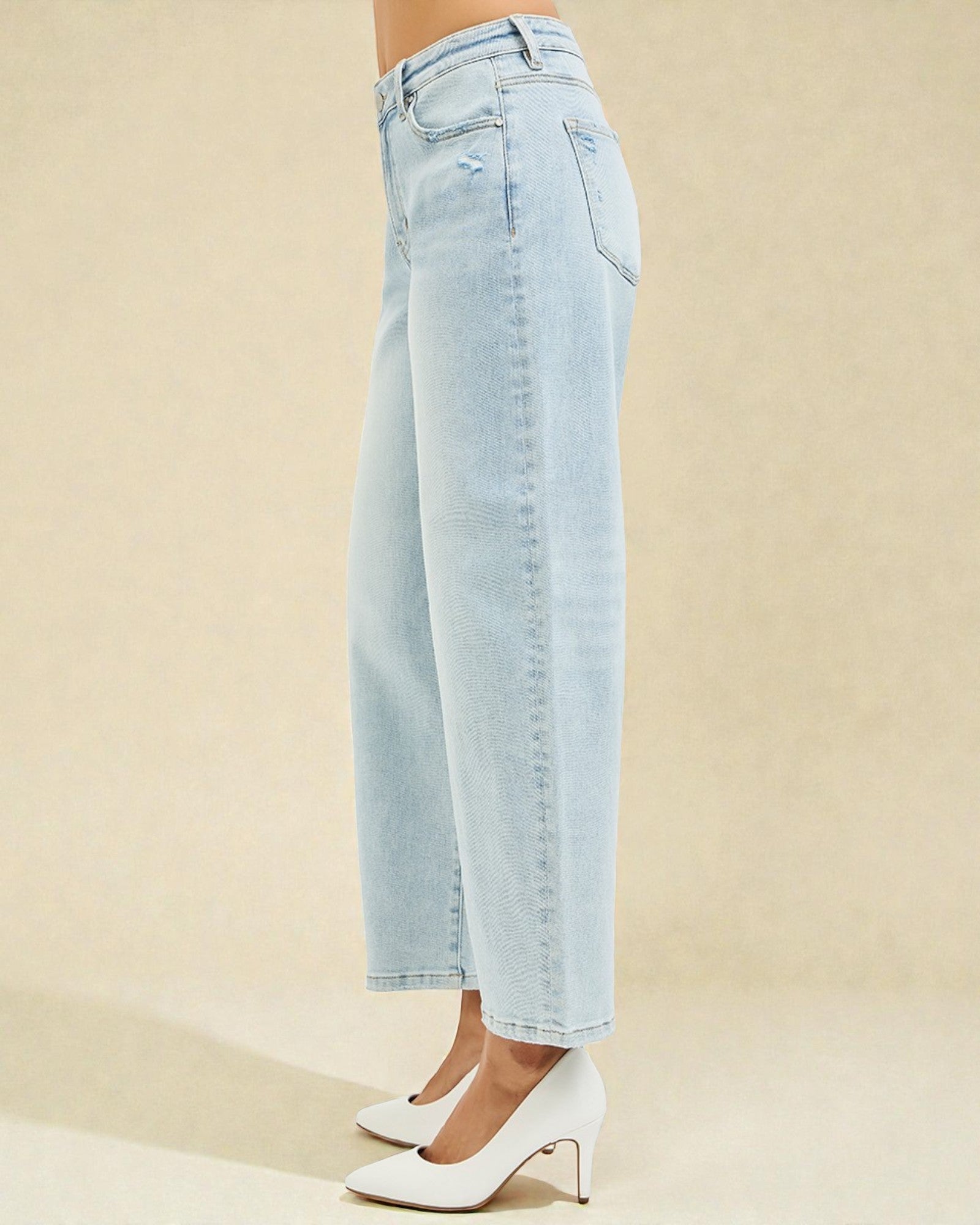 Light blue jeans worn by a person on a beige background