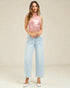 Woman wearing a pink sleeveless top and light blue jeans on a beige background